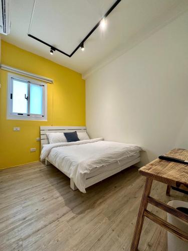 a bedroom with a bed and a yellow wall at 山有巷宅 Alley House in Puli