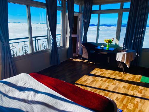 a bedroom with a bed and windows with a view at Panoramic View Guest House Sarangkot in Pokhara