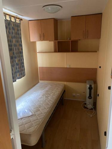 a small room with a bed and wooden cabinets at Mobil-Home standard in Voyennes