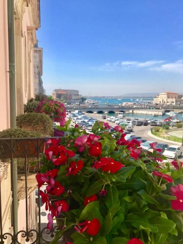 a balcony with red flowers and a view of a city at Hotel Posta in Siracusa