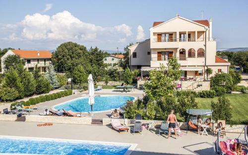 een uitzicht op het zwembad in een resort met mensen op stoelen bij Pansion Skelin in Drinovci