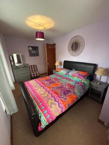a bedroom with a large bed with a colorful blanket at Old Dairy in Tain
