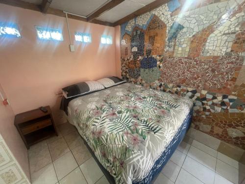 1 dormitorio con 1 cama y una pared de mosaico en CABAÑAS TIA FLOR, en Pica