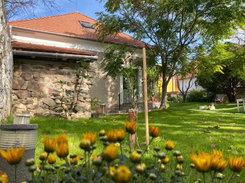 ein Haus mit einem Garten mit Blumen im Gras in der Unterkunft Hatablak Köveskál in Köveskál