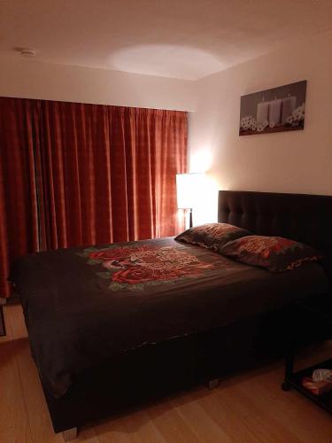 a bedroom with a bed and a window with red curtains at studionusi in Blankenberge