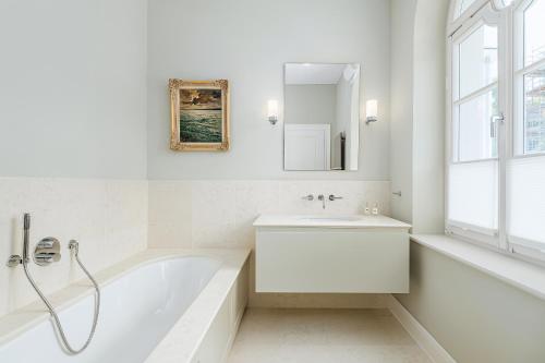 a white bathroom with a tub and a sink at Villa Schwan Wohnung 03 in Heiligendamm
