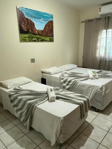 três camas num quarto com um quadro na parede em HOTEL TURISMO MT em Chapada dos Guimarães