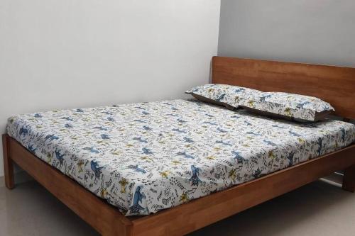 a bed with a wooden frame with a floral comforter at Compact yet beautiful 1bhk 305 in Bangalore