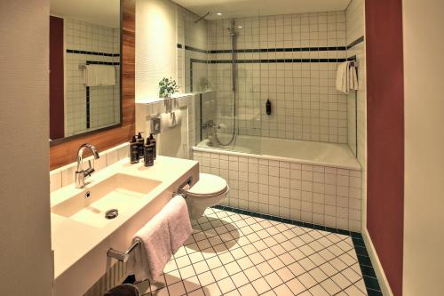 a bathroom with a sink and a toilet and a tub at Mercure Tagungs- & Landhotel Krefeld in Krefeld