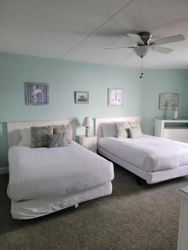 Nassau Inn في وايلدوود كريست: غرفة نوم بسريرين ومروحة سقف