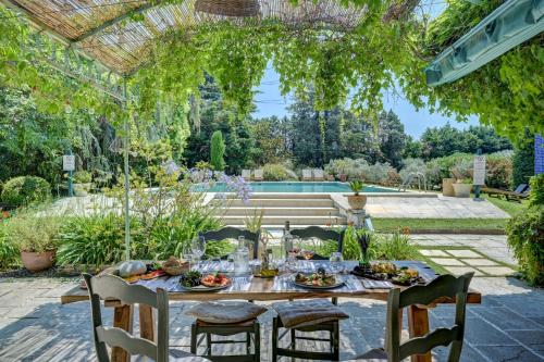 a table and chairs in a garden with a pergola at Hotel Moulin d'Aure in Saint-Rémy-de-Provence