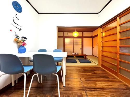 a dining room with a white table and blue chairs at guesthouse森之宮【青丸】 in Osaka