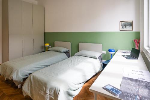 Cette chambre comprend 2 lits et une table avec un ordinateur portable. dans l'établissement [700mStazioneCentrale]Ampio Trilocale con 2Balconi, à Trieste