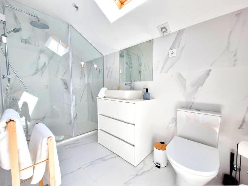 a white bathroom with a toilet and a shower at Tílias House in Covilhã