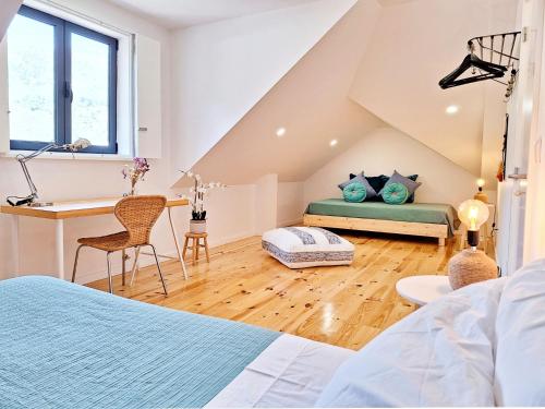 a attic bedroom with a bed and a desk at Tílias House in Covilhã