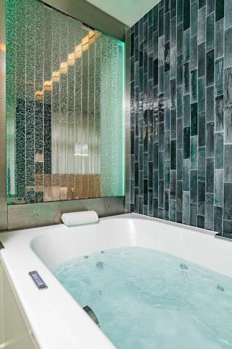 La salle de bains est pourvue d'une baignoire avec un mur en verre. dans l'établissement Citihome Alésia, à Paris