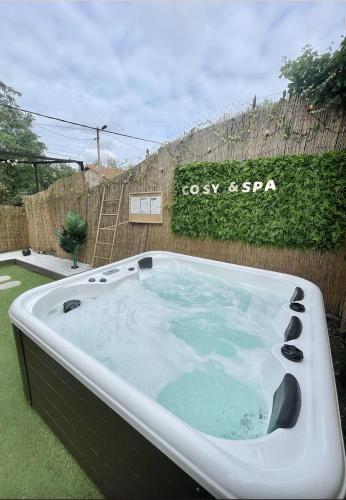 a hot tub in a yard next to a fence at Le Golf Sauna - Cosy & SPA - 1 chambre - 2 pers in Saint-Étienne