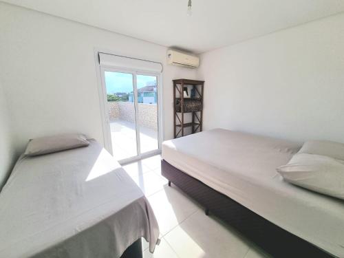 two beds in a room with a balcony at Ed. Fabiana - Ap 301 in Florianópolis