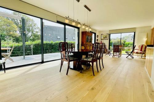 - une salle à manger avec une table, des chaises et de grandes fenêtres dans l'établissement Ti Bras - la grande maison, à Crozon