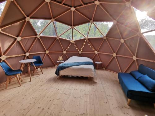 1 dormitorio en una yurta con 1 cama y sillas en La Parenthèse Meslandaise en Mesland