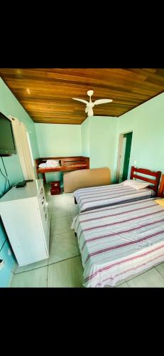 a bedroom with two beds and a flat screen tv at Casa de Temporada Arraial do cabo in Arraial do Cabo