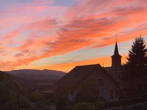 a church with a sunset in the background at Du Vent Dans Les Arbres -120m2 Belle vue sur le lac in Chindrieux