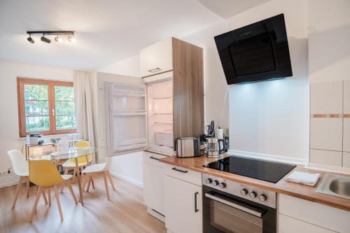 une cuisine avec des placards blancs et une table avec des chaises dans l'établissement Neues Design-Apartment, Altstadt, Business&Ferien, Küche, Netflix, à Bad Säckingen