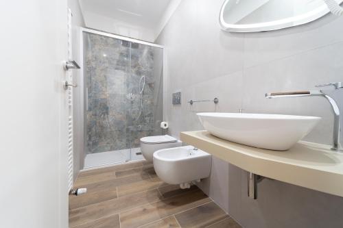 a white bathroom with a sink and a toilet at Mentana Rooms in Parma