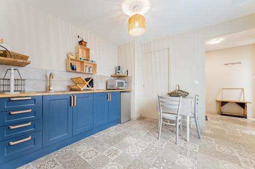 une cuisine avec des armoires bleues et une table et des chaises dans l'établissement La Perle de Lens - Belle maison avec grande terrasse, à Lens