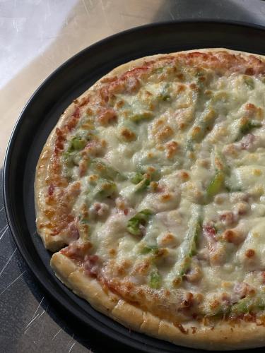 a pizza with cheese and broccoli in a pan at Wind's House Ha Giang in Ha Giang