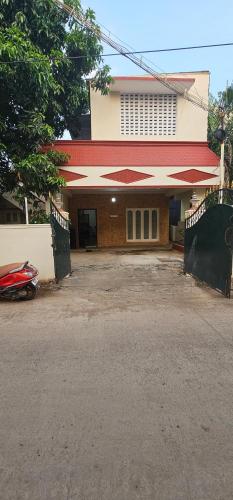 a building with a red roof and a driveway at HOMESTAY - AC 3 BHK NEAR AlRPORT in Chennai