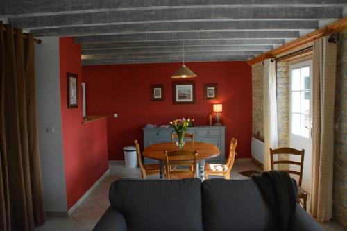 a dining room with a table and a red wall at Les Chaufourniers/L'Etable in Crouay