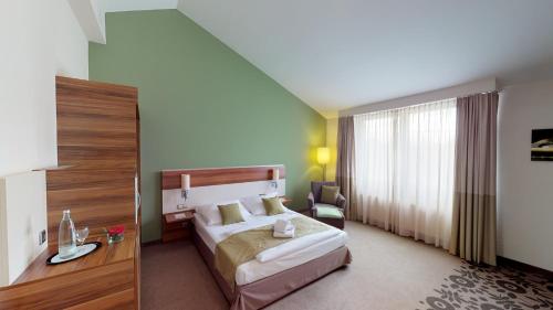 a hotel room with a bed and a chair at Mercure Tagungs- & Landhotel Krefeld in Krefeld