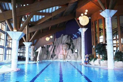 a swimming pool with a waterfall in a building at Résidence Le Médian - Les Ménuires in Les Menuires