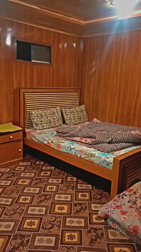 Cama en habitación con pared de madera en Northern Huts And Riverview Restaurant, en Bālākot