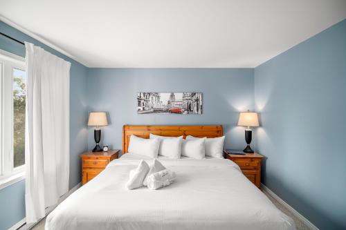 a bedroom with a large bed with blue walls at Townhouse On The Golf W Pool Access -aiglon 1666 in Mont-Tremblant