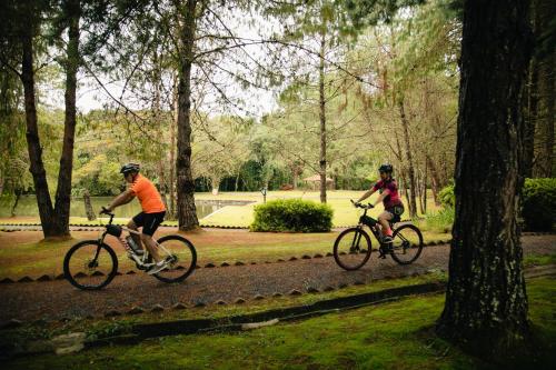 two people riding bikes down a path in a park at Pousada O Cantinho da Raposa in Monte Verde