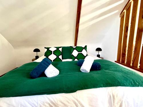 a green bed with soccer pillows on it at Gîte Fancy, Vallée du Scorff, Nature 2-4 personnes in Arzano