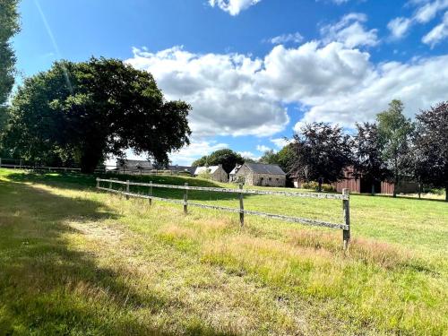 a wooden fence in a field with houses in the background at Gîte Fancy, Vallée du Scorff, Nature 2-4 personnes in Arzano