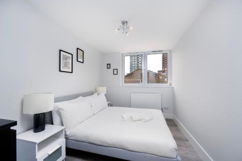 a white bedroom with a bed and a window at Charming Apartment in the Pleydell Estate in London