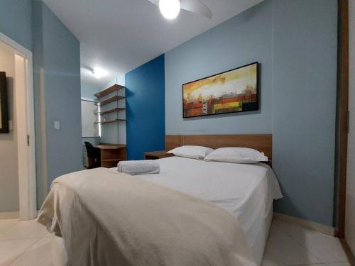1 dormitorio con cama blanca y pared azul en APÊ BLUE (8min a pé da Praia do Forte), en Cabo Frío
