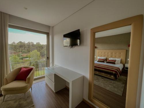 a bedroom with a bed and a desk and a window at Quinta de VillaSete in Alpendurada