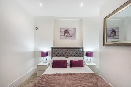 a bedroom with a large bed with two purple pillows at Modern South Kensington Apartment in London