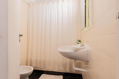 Baño blanco con lavabo y aseo en Fliphaus Borges 2200 - Petit Apt Palermo Soho en Buenos Aires