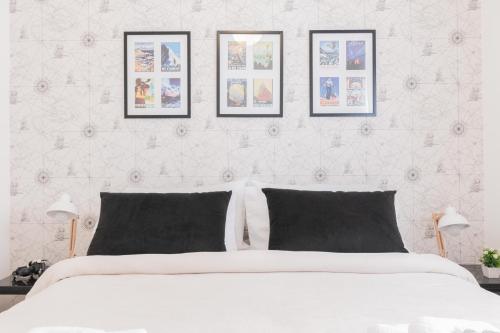 1 dormitorio con 1 cama blanca y 4 cuadros en la pared en Fliphaus Borges 2200 - Petit Apt Palermo Soho en Buenos Aires