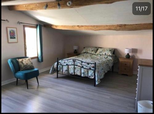 un dormitorio con una cama y una silla en La Maison Tourouzelle, en Lauraguel