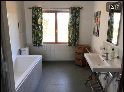 y baño con bañera, 2 lavabos y bañera. en La Maison Tourouzelle, en Lauraguel