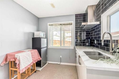 a kitchen with a sink and a black refrigerator at Calgary Mountain Gorgeous Single House Close Airport & Free Parking in Calgary