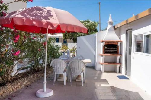 un patio con mesa, sillas y sombrilla roja en BLife Faro Beach Hostel en Faro