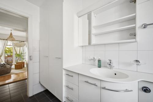 Baño blanco con lavabo y espejo en Dohlenweg 2 en Zúrich
